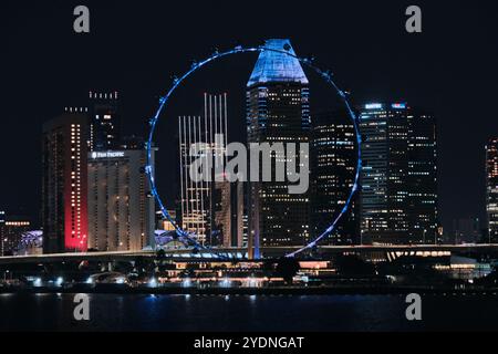 Singapore - 16 agosto 2024: Skyline della città e ruota panoramica Singapore Flyer sulla Marina Bay di notte Foto Stock