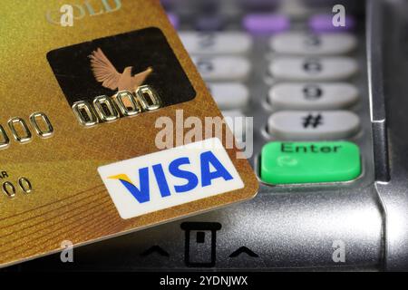 Logo VISA sulla carta di credito con terminale di pagamento sullo sfondo Foto Stock