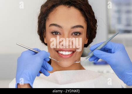 Sorridente donna africana e dentista mani con gli strumenti Foto Stock