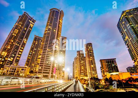 Lungo il fiume principale, attraversa uno dei quartieri centrali più esclusivi di Manila, i condomini e gli uffici si illuminano, illuminati in modo luminoso Foto Stock