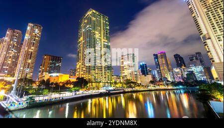 Lungo il fiume principale, attraversa uno dei quartieri centrali più esclusivi di Manila, i condomini e gli uffici si illuminano, illuminati in modo luminoso Foto Stock