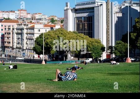 Pomeriggio rilassato al Parco Alameda, Lisbona, con persone che si rilassano sull'erba sullo sfondo di architettura storica e moderna Foto Stock