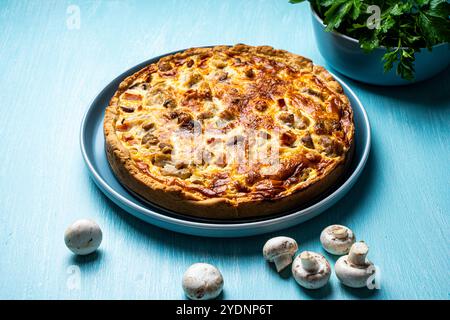Quiche Laurent secondo una ricetta tradizionale francese. Torta di pollo e funghi su un piatto blu con prezzemolo e parmigiano su un backgroun blu Foto Stock