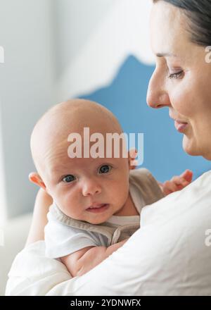 Madre tenera e amorevolmente tiene in braccio il suo bambino appena nato. Primo piano della faccia dei bambini Foto Stock