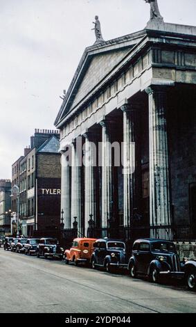 La Pro Cathedral in Marlboro Street, Dublino, Irlanda, fotografò nel 1957 con auto dell'epoca parcheggiate fuori dalla chiesa. Più avanti lungo la strada c'è un cartello per Tylers Shoe Store. Foto Stock