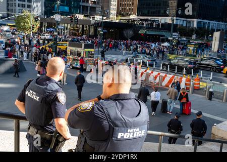 New York, New York, Stati Uniti. 27 ottobre 2024. Folle di sostenitori di Donald Trump, molti con berretti e camicie marchiati MAGA o Trump, si riuniscono fuori dal Madison Square Garden prima di un raduno serale. La polizia sui gradini della Moynihan Train Hall si affaccia su una folla di persone fuori dal Madison Square Garden. Crediti: Ed Lefkowicz/Alamy Live News Foto Stock