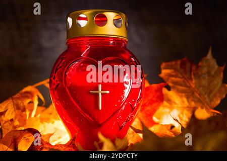 Baviera, Germania - 27 ottobre 2024: Tomba di candela con foglie autunnali. Immagine simbolica per il giorno di Ognissanti e commemorazione del defunto *** Grabkerze mit Herbstlaub. Symbolbild für Allerheiligen und Gedenken an Verstorbene Foto Stock