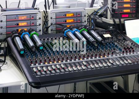Un mixer nero con un supporto per microfono. Il supporto è dotato di un microfono blu e verde Foto Stock