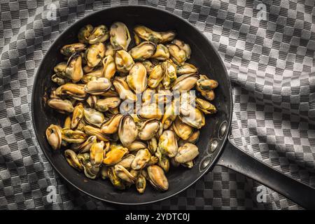 Cozze sgusciate di carne in padella su una tovaglia a scacchi. Vista dall'alto. Foto Stock