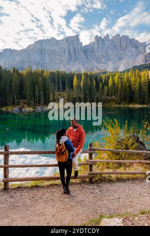 Una coppia gode di un momento sereno insieme in un lago verde smeraldo, circondato da maestose cime dolomitiche e da un vivace fogliame autunnale. Lago di Carezza o Dolomiti di Karersee in Italia. Foto Stock