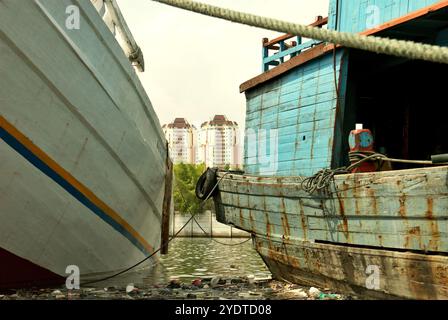 Edifici torreggianti sulla zona costiera di Giacarta sono visti attraverso le barche phinisi al porto tradizionale Sunda Kelapa a Giacarta, Indonesia. Foto Stock