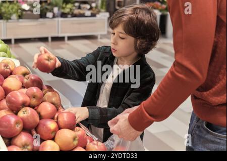 padre e figlio giovane imparano l'importanza di sane abitudini alimentari. momento emozionante in cui selezionano con cura le mele da gustare come un Foto Stock