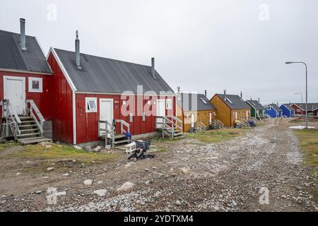 Fila di case colorate lungo una strada sterrata sotto un cielo nuvoloso, remoto insediamento artico Inuit Ittoqqortoormiit, Scoresbysund o Scoresby Sund o Gree Foto Stock
