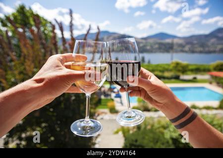 Okanagan Valley wine tasting tour, visita cantine estivi e durante le vacanze di primavera concetto, l uomo e la donna le mani come tostare il vino rosso e bianco bicchieri Foto Stock