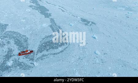 Aerea di una piccola nave che galleggia tra il ghiaccio sotto il ghiacciaio EQI, Groenlandia occidentale, Danimarca, regioni polari Foto Stock