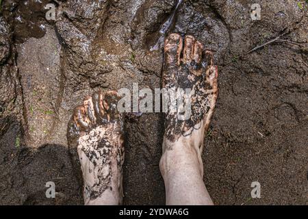Una vista dall'alto verso il basso di una persona a piedi nudi in piedi nel fango sacro e nei fanghi durante un rifugio all'aperto che celebra le culture sciamaniche e indigene Foto Stock