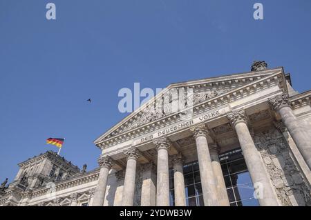 Vista del fronte a colonne dell'edificio del Reichstag con la bandiera tedesca sotto un cielo limpido, Berlino, Germania, Europa Foto Stock