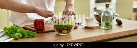 Un giovane uomo prepara sapientemente un'insalata sana in una cucina elegante. Foto Stock