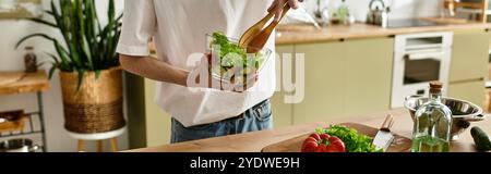 Un giovane uomo mescola sapientemente verdure fresche e verdure in un ambiente luminoso e moderno. Foto Stock