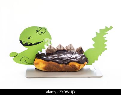 Una torta fatta in casa al gusto di arancia a forma di dinosauro, ricoperta di ricca ganache al cioccolato, perfetta per festeggiare il compleanno di un bambino Foto Stock