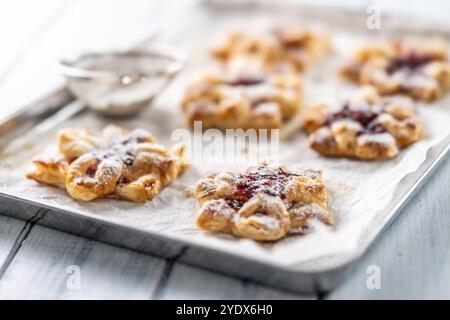 Dolci dolci dolci fatti di pasta sfoglia con marmellata di fragole ripiena di mele caramellate cosparse di zucchero a velo. Foto Stock