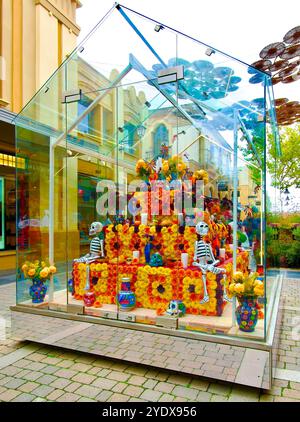 Cabina di vetro con una mostra di scheletri teschi e fiori per la celebrazione del giorno di Halloween dei morti Las Rozas Village outlet shopping Madrid Spagna Foto Stock