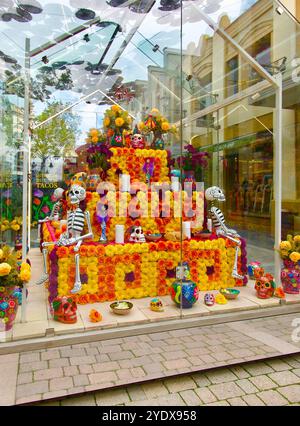 Cabina di vetro con una mostra di scheletri teschi e fiori per la celebrazione del giorno di Halloween dei morti Las Rozas Village outlet shopping Madrid Spagna Foto Stock