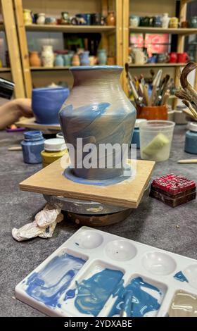 Il processo di pittura di un vaso in ceramica durante una masterclass. Creatività nei dettagli in ogni pennellata, creando un'opera d'arte in ceramica unica Foto Stock