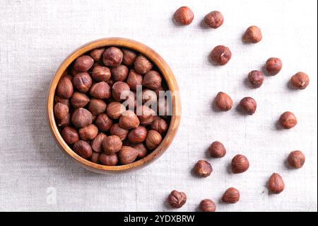 Nocciole, note anche come noci di cocco e filetti, in una ciotola di legno su lino. Frutta secca intera, secca e sgusciata, frutti del nocciolo. Foto Stock