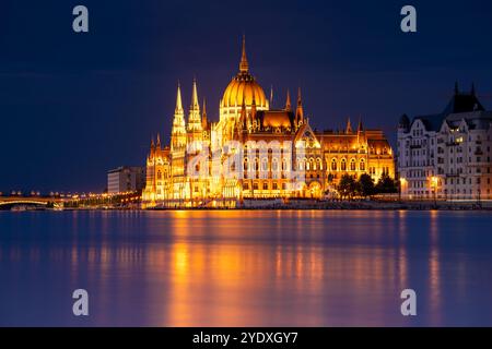 Budapest, Ungheria - 17 settembre 2024: Il Parlamento di Budapest riflette sul Danubio nella notte. Scatto con esposizione notturna prolungata. Foto Stock