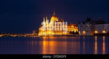 Budapest, Ungheria - 17 settembre 2024: Il Parlamento di Budapest riflette sul Danubio nella notte. Scatto con esposizione notturna prolungata. Foto Stock