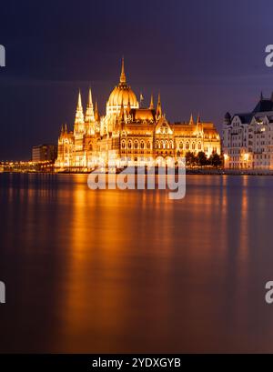 Budapest, Ungheria - 17 settembre 2024: Il Parlamento di Budapest riflette sul Danubio nella notte. Scatto con esposizione notturna prolungata. Foto Stock