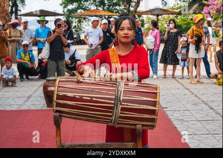 Giovane donna vietnamita in abito rosso che suona un tamburo tradizionale alle po Nagar Cham Towers di Nha Trang in Asia. Nha Trang, Vietnam - 8 agosto 2024 Foto Stock