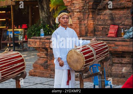 Ritratto di un adolescente musicista vietnamita che suona un tamburo tradizionale al po Nagar Cham Towers Festival di Nha Trang in Asia. Nha Trang, Vietnam - 8 agosto 2024 Foto Stock