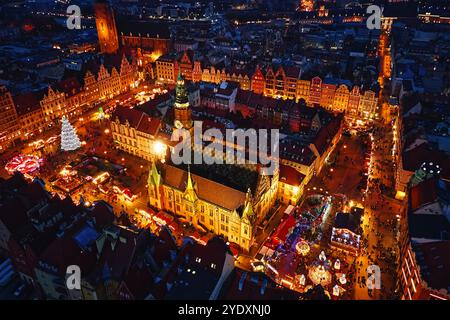 Vista aerea del mercato di Natale di notte con bancarelle illuminate, alberi festivi ed edifici storici a Breslavia, Polonia. Città europea decorata Foto Stock