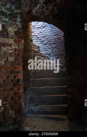 Una stretta scala a chiocciola in mattoni nella fortezza di Bobruisk. La luce del sole all'interno Foto Stock