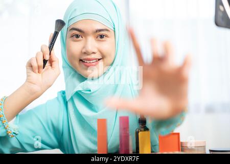 Una giovane beauty blogger sta registrando un video vlog su uno smartphone utilizzando la luce anulare. Sparato attraverso l'anello Foto Stock