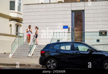 Londra - 06 16 2022: Due ragazze che parlano e ridono di fronte all'Ethos Sports Centre Foto Stock