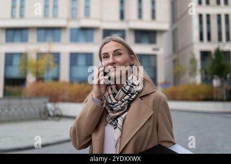 Una donna d'affari cammina vicino a un business center mentre parla al telefono Foto Stock