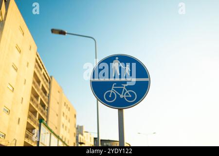 Percorso condiviso per l'uso da parte di pedalate e pedoni solo cartelli metallici sul palo, simboli bianchi su blu Foto Stock