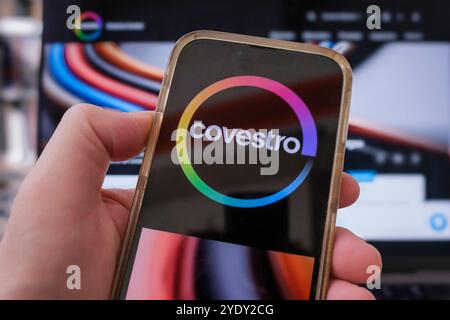 Mano con un telefono cellulare su cui è visibile il logo Covestro Foto Stock