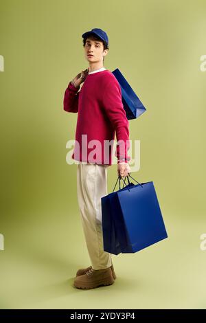 Un giovane alla moda con i capelli ricci tiene in mano le borse della spesa, celebrando lo spirito del Black Friday. Foto Stock