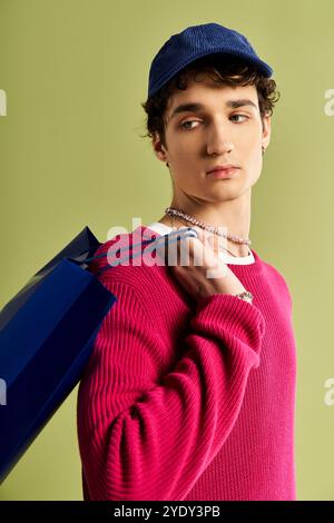 Un bel giovane tiene in mano borse per la spesa il Black Friday, mostrando il suo stile alla moda in uno sfondo da studio. Foto Stock