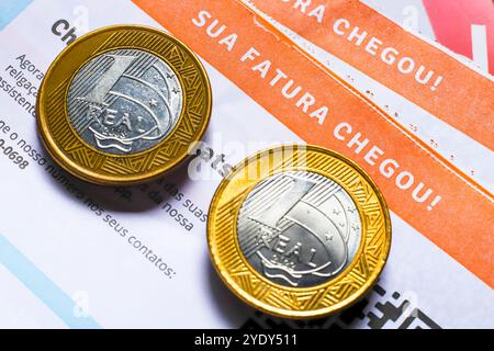 29 ottobre 2024, Brasile. Una bolletta elettrica e una moneta reale (denaro brasiliano) Foto Stock