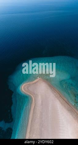 Le limpide acque turchesi si infrangono dolcemente contro la forma unica della spiaggia di Zlatni Rat, una meraviglia naturale sull'isola di Brac. Questo luogo tranquillo attrae gli amanti del sole e della natura, mostrando la bellezza della Croazia. Foto Stock