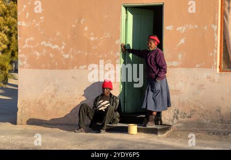 vecchia coppia africana del villaggio che aspetta al sole di fronte alla casa Foto Stock