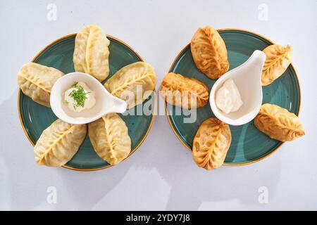 Tradizionale manti kazako al vapore. Due tipi: Bolliti e fritti su piatti verdi. Sfondo bianco Foto Stock