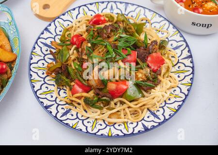 Primo piano sugli spaghetti uiguri laghman in un piatto tradizionale sul tavolo di legno scuro, orizzontale Foto Stock