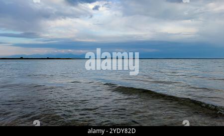 Le calme acque del lago Issyk-Kul riflettono le nuvole e le montagne spettacolari. Silenzio e tranquillità in un'oasi naturale del Kirghizistan. Foto Stock