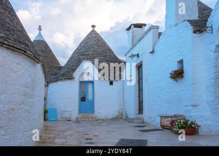 Alberobello, annidato nel cuore della Puglia, le tradizionali case dei trulli si stagliano con orgoglio contro il cielo serale, con i loro tetti conici che aggiungono un fascino unico Foto Stock